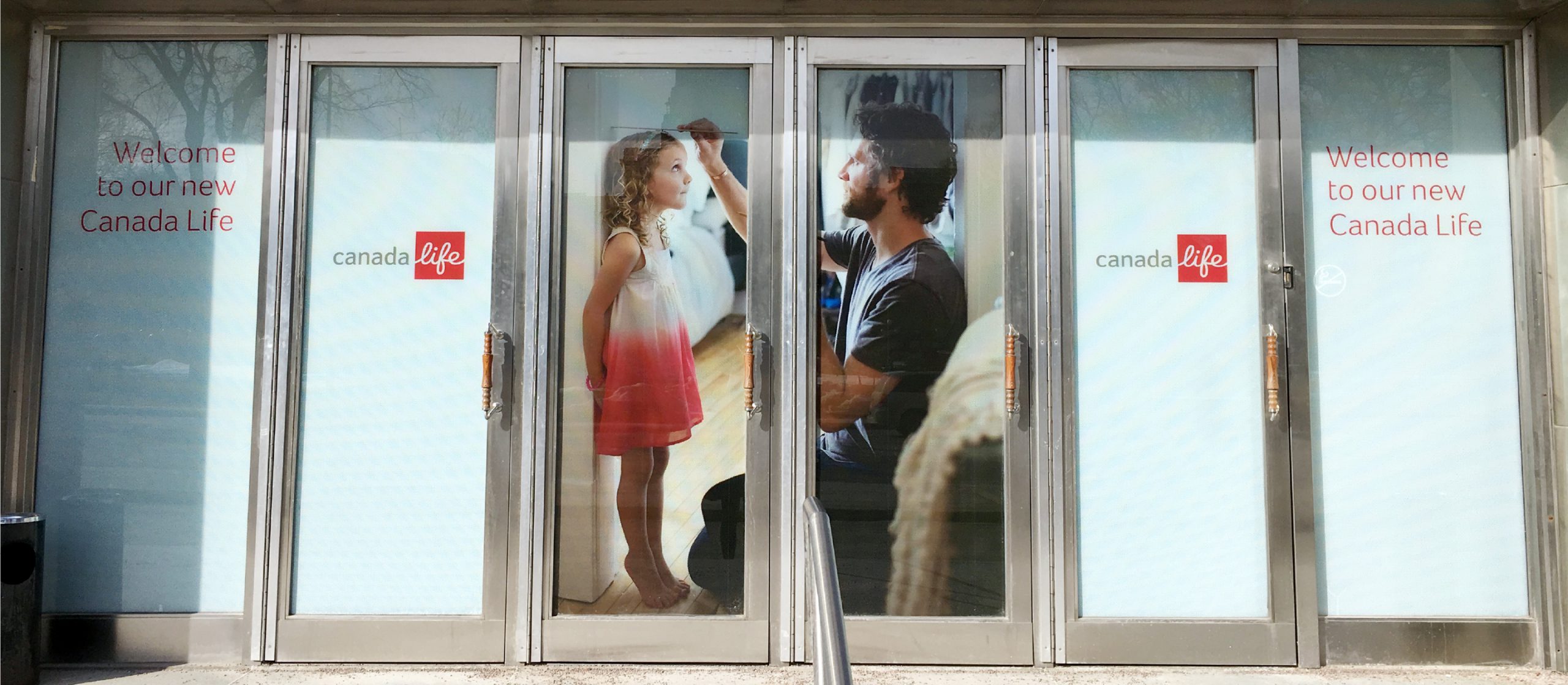 Photo of brand activation with brand visuals and messaging applied to entry doors of a Canada Life office location.