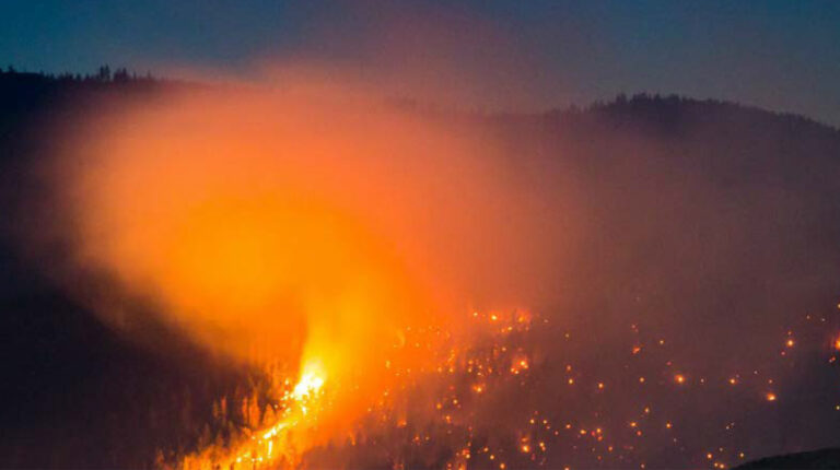 Image of orange glowing forest fires at dusk in British Columbia