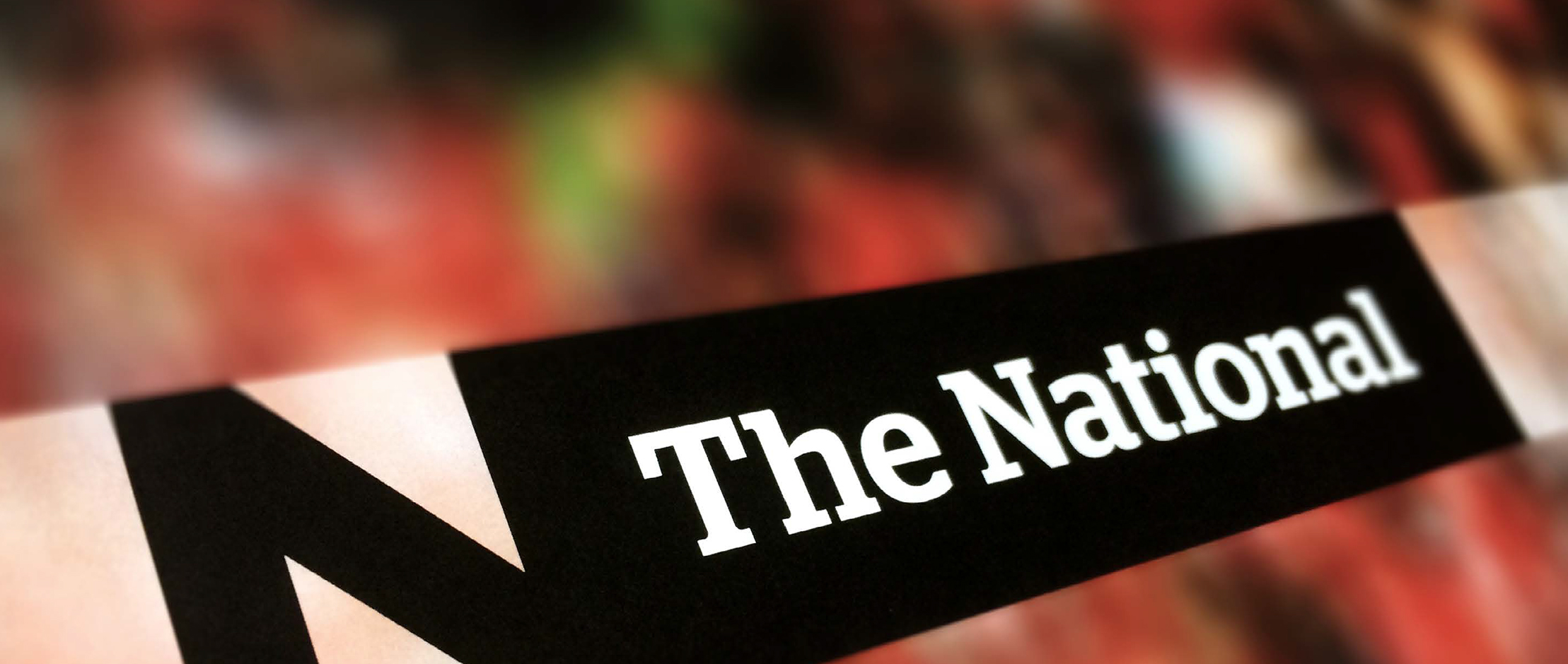 Closeup of the new National logo on a blurred red background.