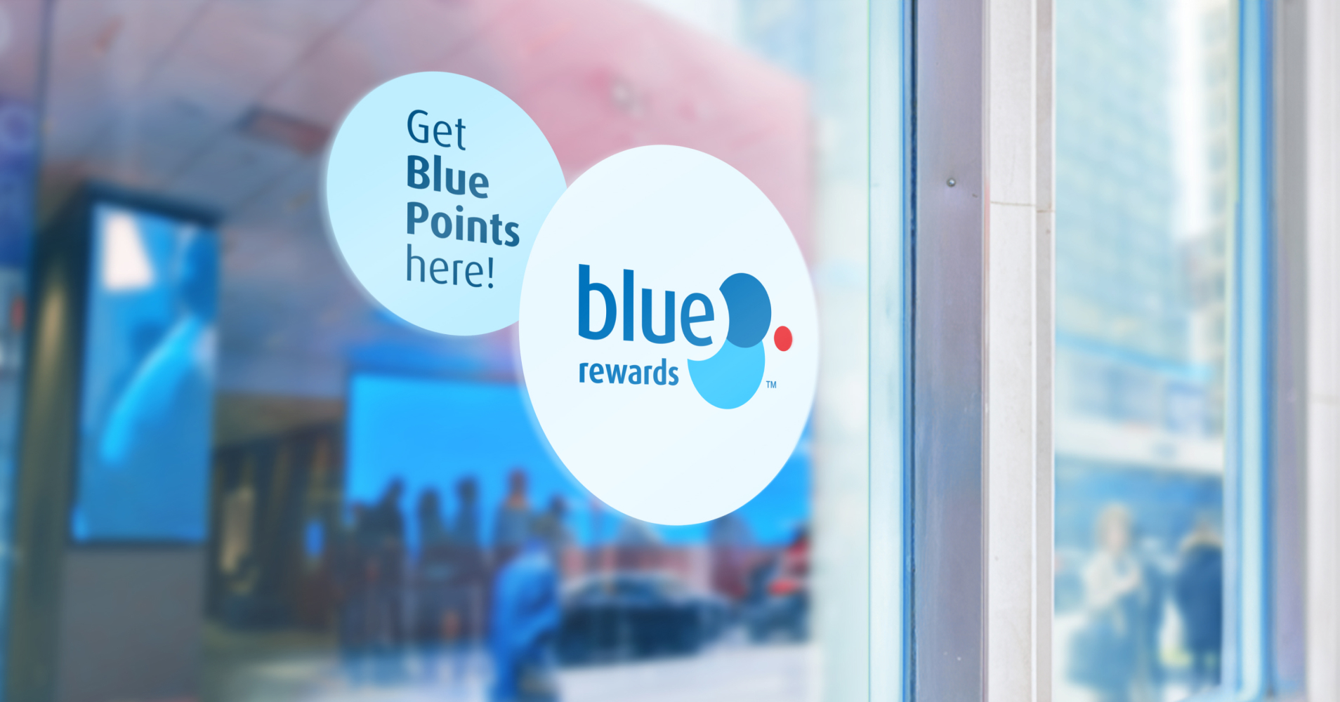 Storefront window showing a decal with 2 light circles that contain the Blue Rewards logo and the text "Get Blue Points here!"